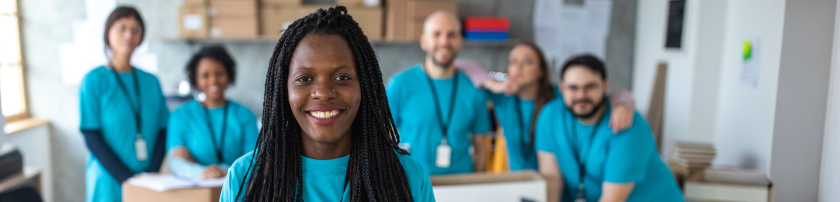 nonprofit worker with long hair standing in front of group of colleagues smiling