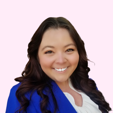 headshot of a woman with long dark hair wearing a bright blue blazer smiling at the camera against a light pink background.