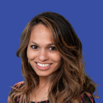 A woman with long dark hair smiling against a blue background.