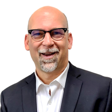 Headshot of Eli, a bald white man with a gray goatee and black glasses looking at the camera and smiling. 