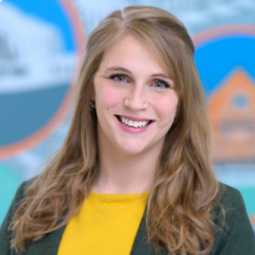 A woman with long blonde hair smiling against a blue and orange background.